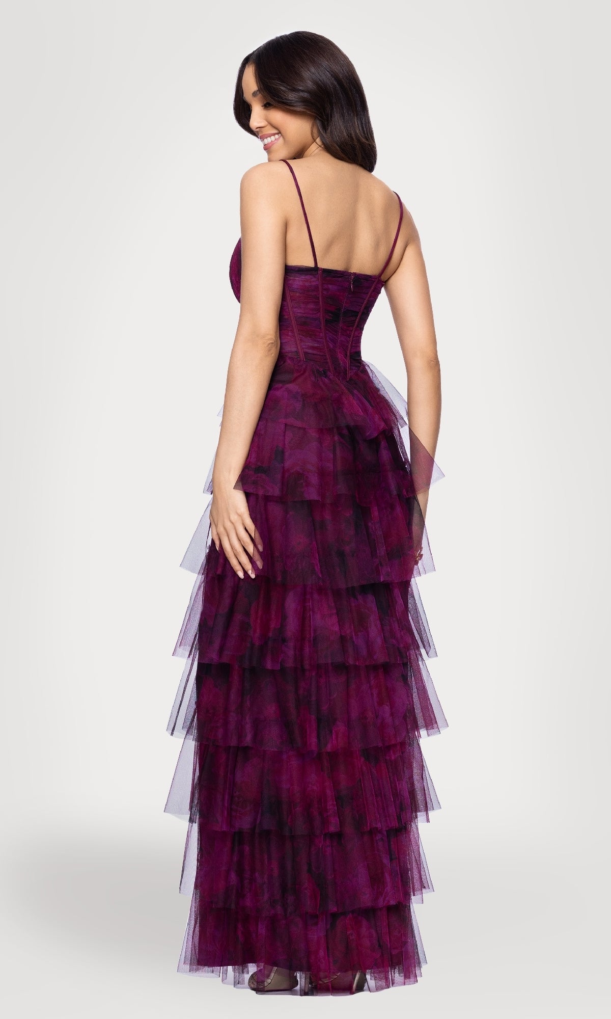 A woman faces away, wearing the Blondie Nites 5778BN Wine Red Ruffle Formal Gown—a sleeveless, floor-length tulle dress with thin straps—set against a plain light background.